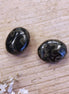 Perle schwarz - oval mit grünen Ölflecken